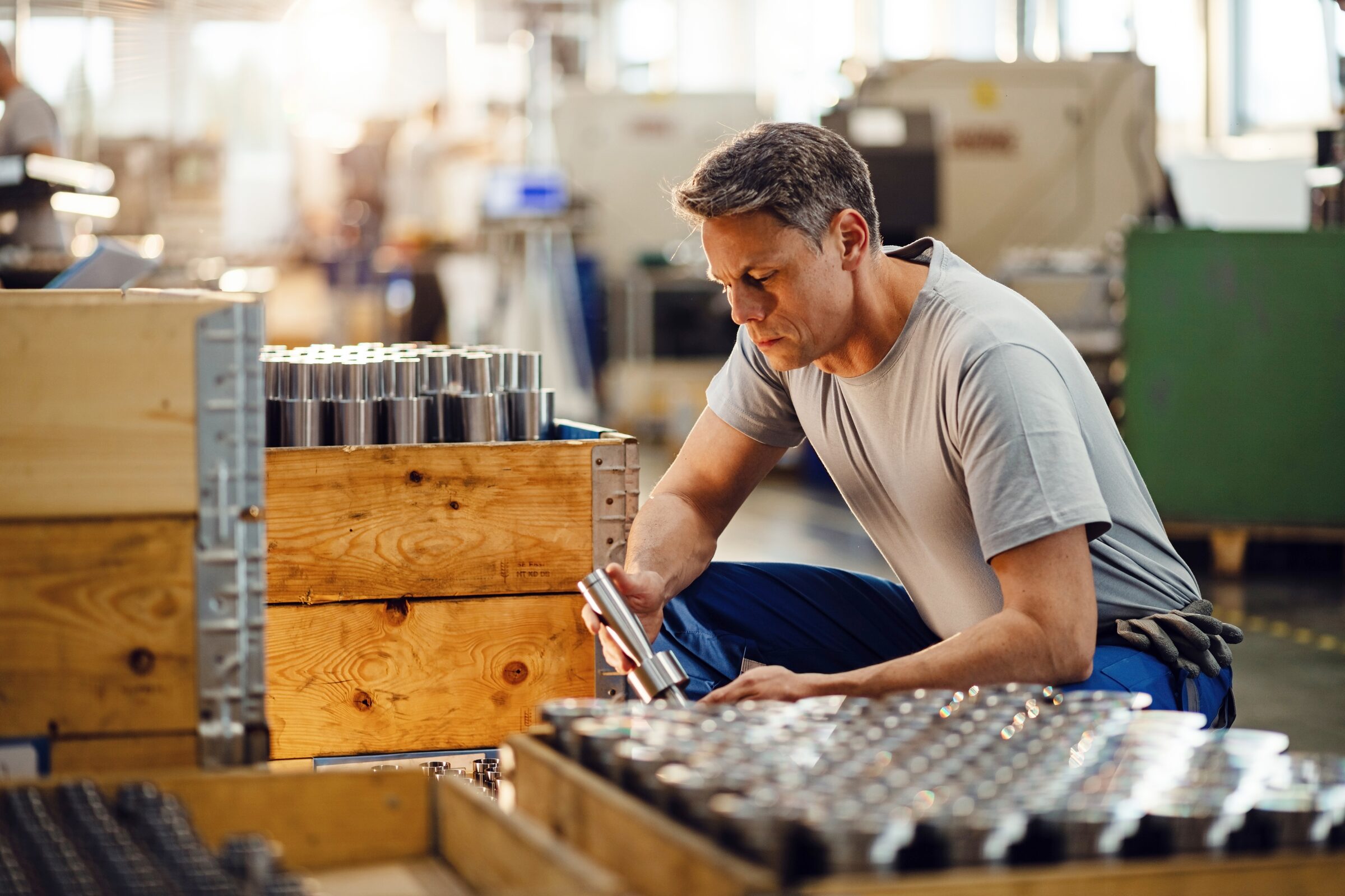Worker packing precision metal components into a wooden shipping crate